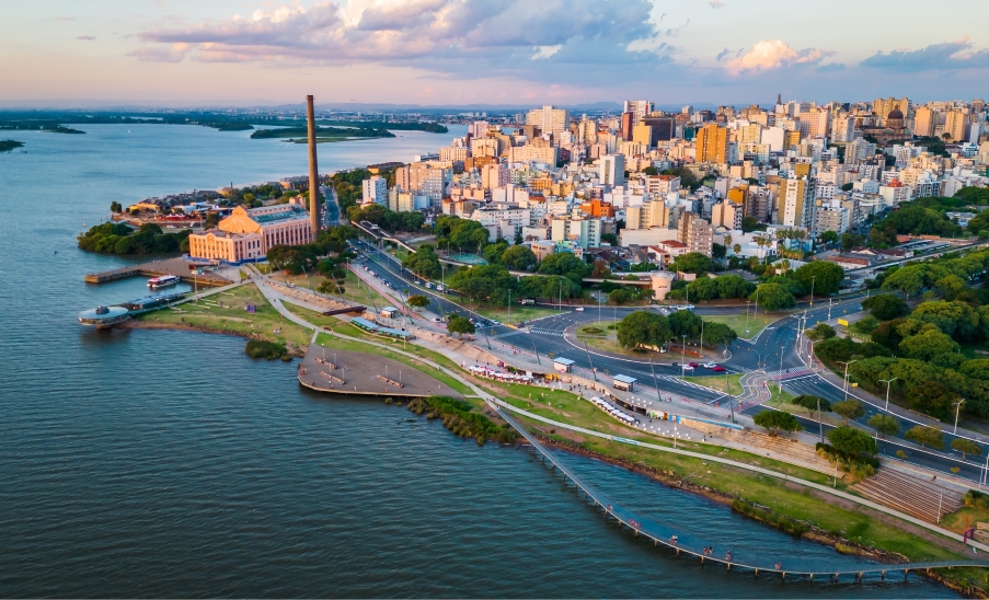 Porto Alegre Aterro do Gasômetro e centro de Porto Alegre vistos do alto, com o Guaíba à esquerda, a Usina do Gasômetro e avenidas arborizadas ao entardecer.