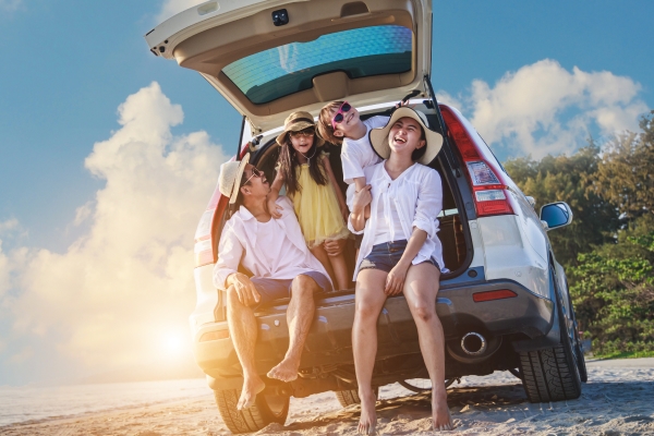 Familia sentada en un auto estacionado en la playa.
