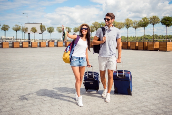 Pareja con maletas caminando por estacionamiento de aeropuerto.