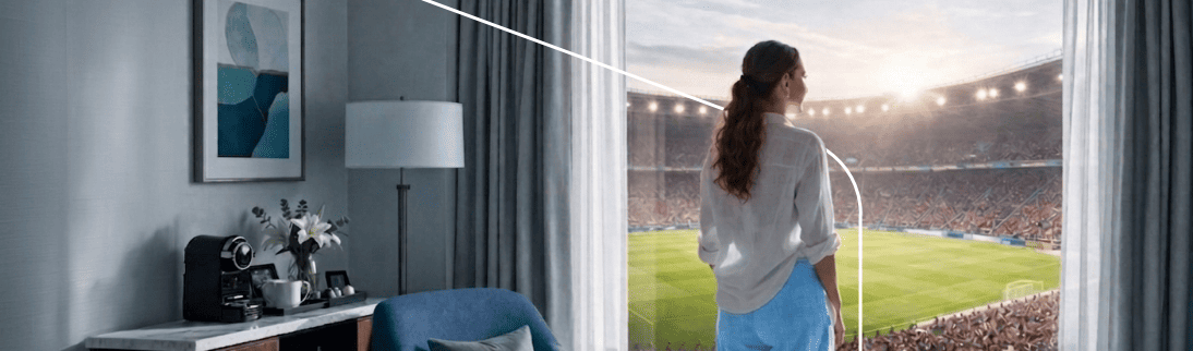 Kansas City Mujer mira por la ventana de una habitación de hotel con vista directa a un estadio
