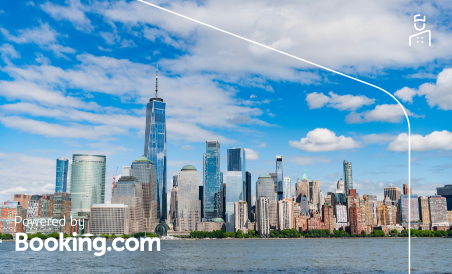 Panorama do skyline de Manhattan com o One World Trade Center em destaque sob um céu azul; “Powered by Booking.com”