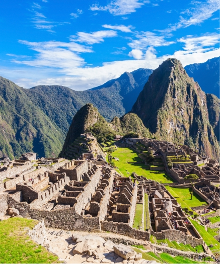 Unmissable full-day tour to Machu Picchu, Cusco Panoramic view of Machu Picchu with green mountains, a clear blue sky, and Inca ruins in the foreground.