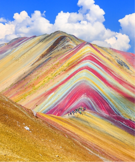1 Day Adventure Tour to the Colorfull Rainbow Mountain View of Rainbow Mountain with red, yellow, and green mineral bands under a clear blue sky.