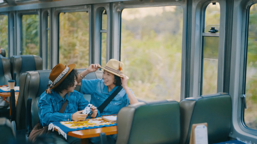 My Peru Story - A New Adventure Tourists on a panoramic train in Peru heading to Machu Picchu, laughing and holding a camera over a colorful Andean tablecloth.