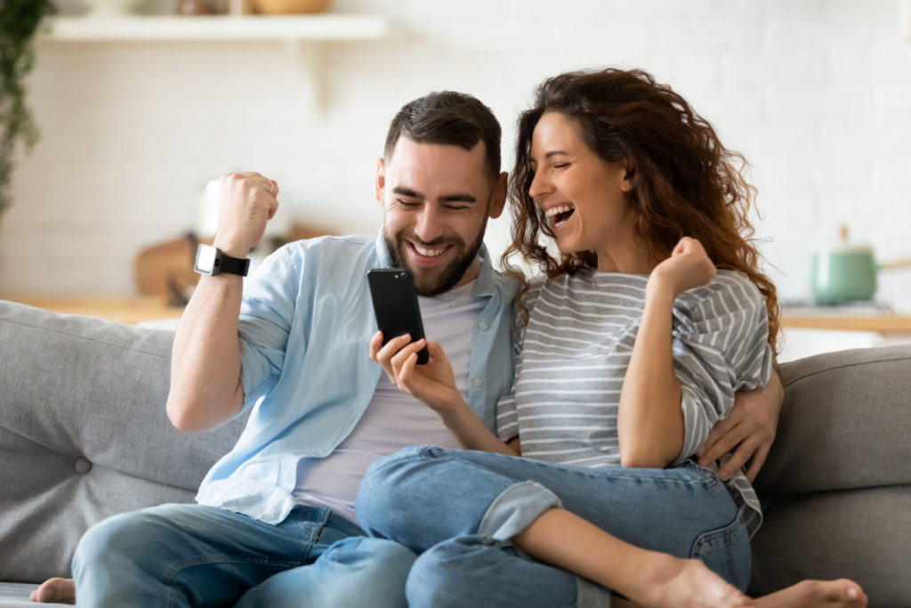 Pareja feliz en sillón con teléfono